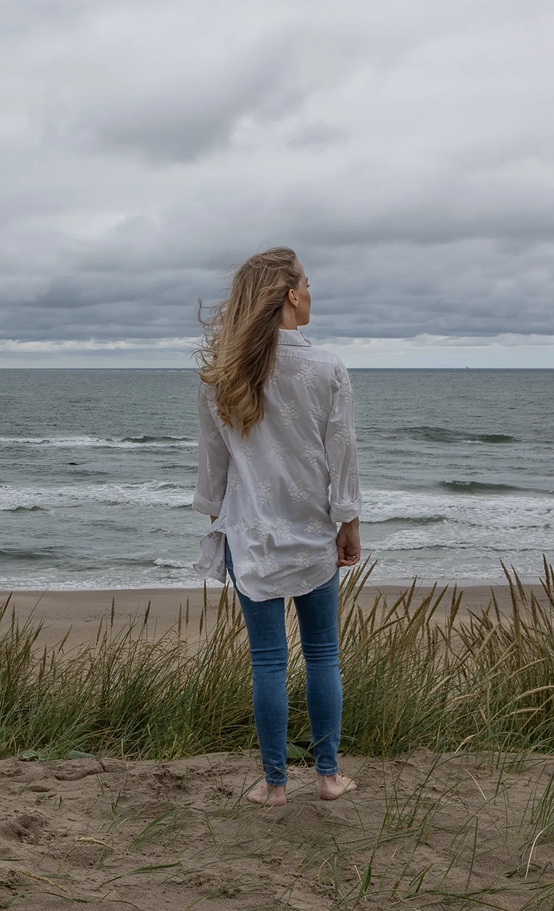 Kvinde står ved Vesterhavet i Hirtshals og ser ud over havet – kontakt psykoterapeut Kristina Gersboell for nærværende samtaleterap